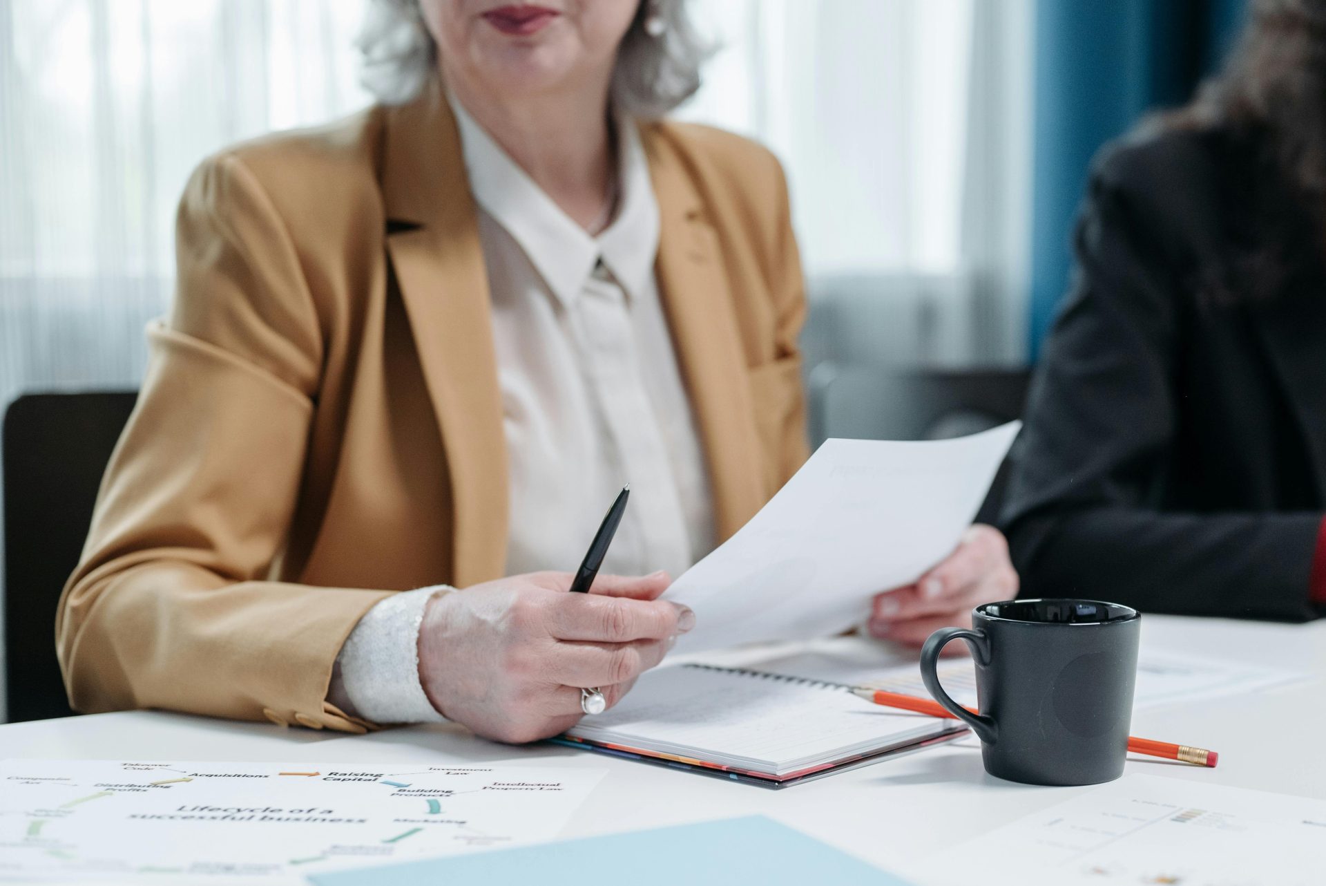 Une femme d'âge mûr examine des documents lors d'une réunion d'affaires, faisant preuve de professionnalisme.